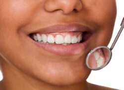 Close-up of woman's mouth being viewed with dental mirror wisdom teeth dentist in Tulsa Oklahoma